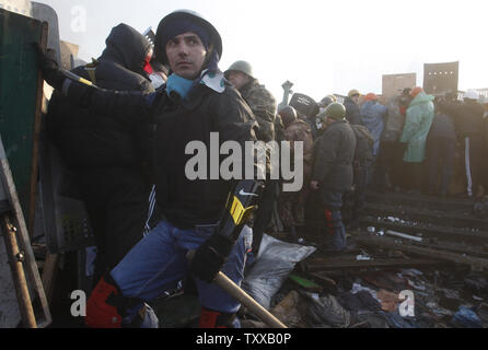 Governo anti-manifestanti a raccogliere una barricata durante gli scontri con la polizia antisommossa a Kiev il 19 febbraio 2014. UPI/Ivan Vakolenko Foto Stock