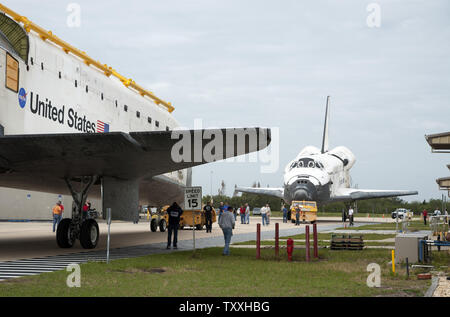 NASA moduli orbitanti 'ATLANTIS' (l) e 'scoperta' soddisfare sul modo di traino tra il gruppo di veicoli Edificio e l'Orbiter Processing Facility al Kennedy Space Center, Florida il 9 marzo 2012. Scoperta, completare con il cono posteriore per migliorare la sua prestazione aerodinamica per il volo, si sta muovendo verso la VAB dove la NASA il completamento dei preparativi per volare scoperta per lo Smithsonian Museum di Steven F. Udvar-Hazy Center all'Aeroporto Dulles a Chantilly, Virginia vicino a Washington DC. Atlantis sta ritornando allo stabilimento di trasformazione per continuare la modifica per visualizzare presso il Kennedy Space Center Visitor Foto Stock