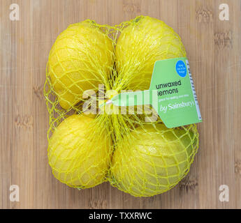 London / UK - 25 Giugno 2019 - Unwaxd limoni da Sainsburys in un pacco di quattro su uno sfondo di legno Foto Stock