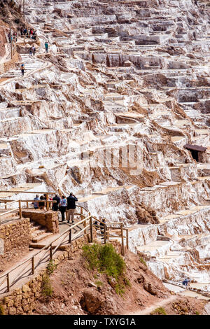 I turisti che visitano salineras de Maras / Maras Miniere di Sale. Estrazione del sale a Maras saline, terrazze e stagni, Perù Valle Sacra. Foto Stock