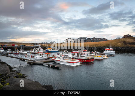 Vista di un piccolo porto di pesca in Islanda al tramonto. Alcune case sono visibili in background. Foto Stock