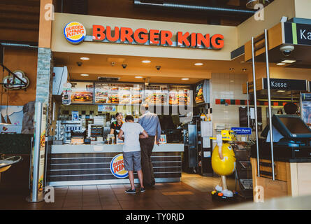 Stuttgart, Germania - 15 AGO 2018: vista posteriore del Padre e del figlio presso il contatore di Burger King ristorante al distributore Esso in Germania in attesa di mettere ordine e ottieni il fast-food lontano Foto Stock