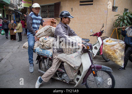 Hanoi, Vietnam - Dicembre 23, 2013: lavoratore edile che trasportano il loro materiale su uno scooter nelle strette strade di Hanoi, Vietnam Foto Stock