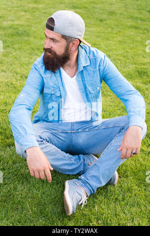 Hipster stile di vita. Cool Parigamba con la barba usura Elegante berretto da baseball. Brutale bello hipster uomo in appoggio sul giorno di estate. Uomo Barbuto trendy hipster stile. Guy abito moderno. Informale e confortevole. Foto Stock