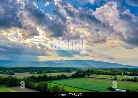 Nuvole drammatico al di sopra del paesaggio rurale, raggi del sole attraverso le nuvole, siepi e pascoli, tranquillo paesaggio, campagna in Slovenia Foto Stock