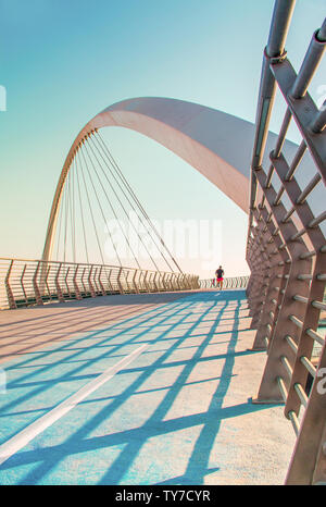 Dubai famoso ponte di tolleranza in prossimità di acqua canal giovane uomo che corre sul ponte al tramonto architettura moderna Foto Stock