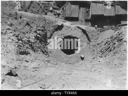 Guardando verso il basso nello scavo per Nevada a valle della torre di aspirazione. Vista mostra scavo circolare per aspirazione sulla fondazione della torre e lo scavo di tunnel 41 piedi di diametro che porterà il condotto di elevazione a potenza di 820 penstock testata.; Portata e contenuto: fotografia dal volume due di una serie di album di foto per documentare la costruzione della Diga di Hoover, Boulder City, Nevada. Foto Stock