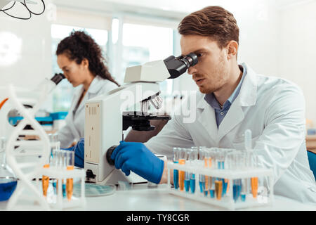 Bel giovane cerca nel microscopio Foto Stock