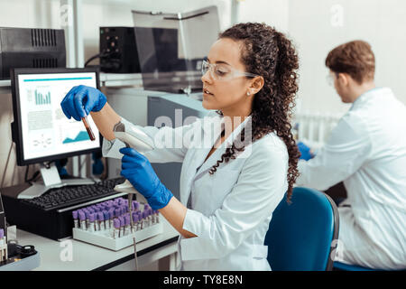 Intelligent giovane donna la scansione del tubo di prova Foto Stock