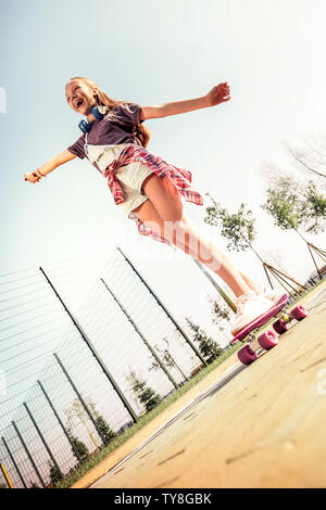Ridere ragazza dai capelli scuri in estate outfit essendo eccitato con riding Foto Stock