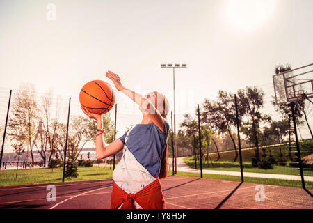 Coinvolti dai capelli scuri ragazza sportive migliorare le sue abilità nel gioco del basket Foto Stock