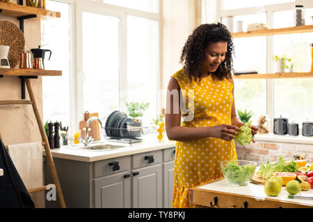 Donna incinta di lattuga di chopping per rendere alcune insalata. Foto Stock