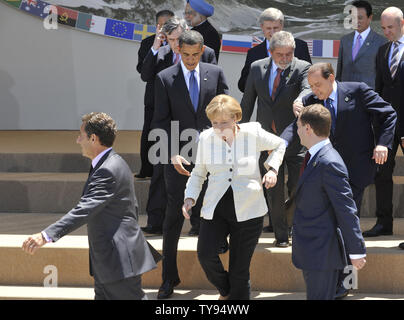 Stati Uniti Il presidente Barack Obama (2 L) con il Primo Ministro italiano Silvio Berlusconi aiuta il Cancelliere tedesco Angela Merkel a lasciare uno stadio dopo G8 e G5 leader foto di gruppo in occasione del vertice del G8 a L'Aquila, Italia il 9 luglio 2009. (UPI foto/Alex Volgin) Foto Stock