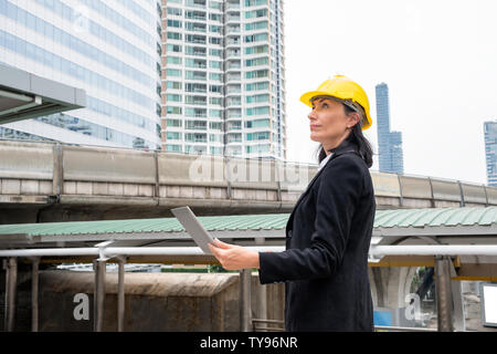 Donna ingegnere con casco azienda stand portatile su sky train nella città Foto Stock