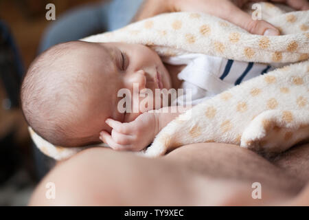 Giovane padre tenendo la sua dolce slepping adorabile bambino neonato. Riprese in interni, il concetto di immagine Foto Stock