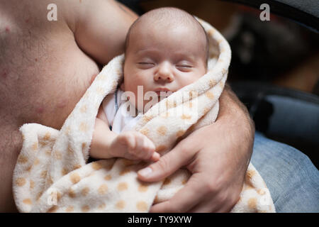 Giovane padre tenendo la sua dolce slepping adorabile bambino neonato. Riprese in interni, il concetto di immagine Foto Stock