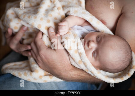 Giovane padre tenendo la sua dolce slepping adorabile bambino neonato. Riprese in interni, il concetto di immagine Foto Stock