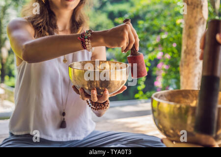 Il Nepal in rame di Buddha Singing Bowl a spa salone. Giovane bella donna facendo terapia di massaggio SINGING BOWLS nella Spa contro una cascata. Terapia del suono Foto Stock