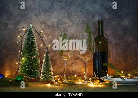 Vino rosso sul tavolo con albero di Natale. Tavolo da pranzo e luci di Natale. Foto Stock