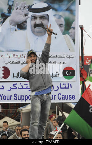 Un libici lampeggia un segno V accanto a un poster del Qatar di Emiro Sheikh Hamad bin Khalifa al Thani come suo assiste un rally contro il leader libico Muammar Gheddafi a Bengasi, Libia, il 28 aprile 2011. UPITarek Alhuony. Foto Stock