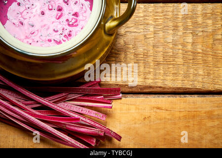 Vecchio vaso con freddo zuppa di barbabietole con giovani bietole sul tavolo di legno Foto Stock