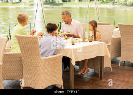 Nipoti gustando la prima colazione vicino al lago con i nonni Foto Stock