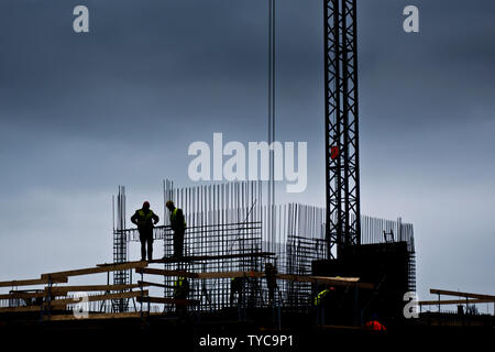 Silhouette di due lavoratori sulla parte superiore di un edificio in costruzione Foto Stock