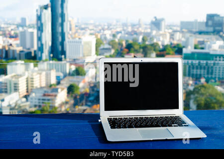 Laptop e bicchiere di cocktail estivi sul tavolo di legno, in bright bello sfondo panoramico della città di Pattaya, Thailandia. Foto Stock