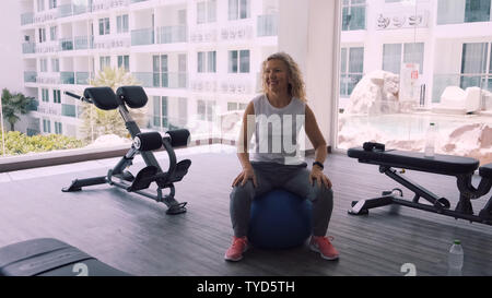 Pattaya, Tailandia - 15 Maggio 2019: donna anziana rende squattings in palestra. Donna anziana donna Senior fa un sport esercizi in palestra. Foto Stock