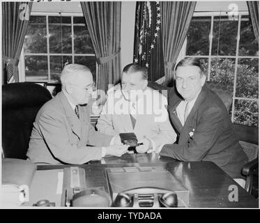 Fotografia del Presidente Truman alla sua scrivania in ufficio ovale, di ricevere il suo abbonamento annuale al National Football League giochi da Bert Bell, Commissario della National Football League (centro) e George Marshall, proprietario del Washington Redskins. Foto Stock