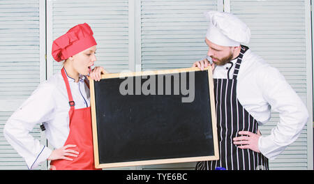 Questa classe vi ispirerà. Master cucinare e cuocere prep dando lezioni di cucina. Chef e cuoco insegnamento helper master class. Paio di uomo e donna azienda lavagna vuota nella scuola di cucina, copia dello spazio. Foto Stock