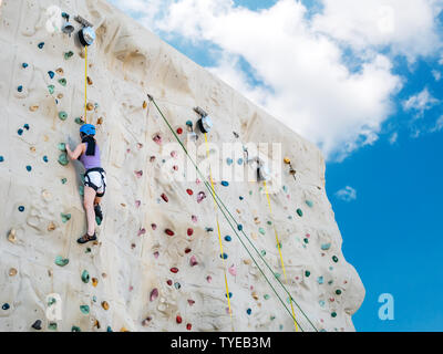 Asian athletic donna pratica di arrampicata su una parete di roccia, attività outdoor con cielo blu, sfondo a basso angolo di visione Foto Stock