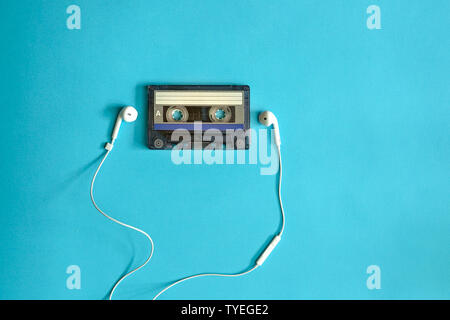 Vecchia cassetta con auricolari su sfondo blu. Andare retrò vintage o ascoltare la musica del concetto. Foto Stock