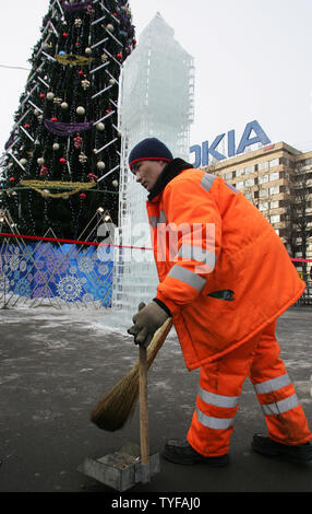 Un lavoratore pulisce la strada vicino a sei metri di altezza la scultura di ghiaccio del Big Ben di Londra la torre dell orologio è impostata in piazza Pushkin a Mosca, 11 gennaio 2006. La scultura è stata una parte di un progetto congiunto con Mosca del governo della città e il sindaco di Londra dell'ufficio. (UPI foto/Anatoli Zhdanov) Foto Stock