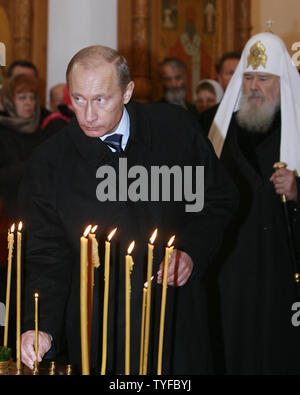 Con il Patriarca ortodosso russo Alexiy II in background il Presidente Vladimir Putin pone una candela durante un memoriale di servizio in Butovo, un sito a sud di Mosca, il 30 ottobre 2007. Il Butovo poligono di tiro è stato utilizzato per esecuzioni dal 1930 fino a dopo la morte di Stalin nel 1953. Alcuni 20.000 persone tra sacerdoti e artisti, sono stati uccisi nel 1937-38 da soli. (UPI foto/Anatoli Zhdanov). Foto Stock