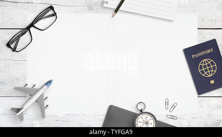 Un foglio di carta pulito mockup, per il logo o il testo di promozione. Piano di viaggio concetto composizione bianco su un tavolo di legno. Modello di aeroplano, passaporto, bussola, bicchieri, pad Foto Stock