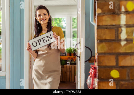 Donna sorridente tenendo la piastra di segno con word aperto. Foto Stock
