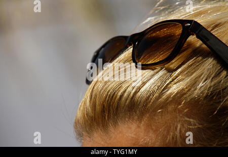 Close-up di donna bionda con occhiali da sole tra i capelli Foto Stock