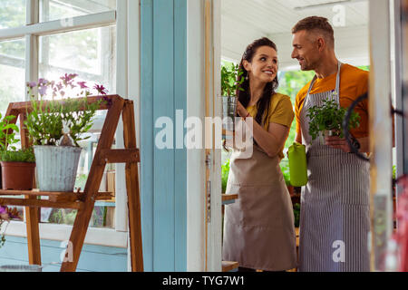 Coppia felice che si aiutano reciprocamente in corrispondenza di un negozio di fiori. Foto Stock