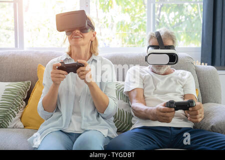 Due anziani gioiosa la riproduzione di video giochi seduto su un divano. Foto Stock