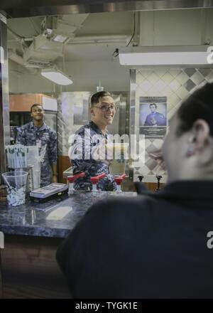 NEWS, Va. (nov. 2, 2016) Il Marinaio Timothy Rose, un marinaio a bordo della Nimitz-class portaerei USS Abraham Lincoln (CVN 72), da Chrisfield, Maryland, mani una bevanda per un cliente della tremolante Abe, un coffee shop a bordo Lincoln. Lincoln è nelle fasi finali di completamento di un rifornimento e complesso di revisione. Foto Stock