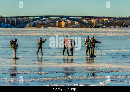 Un gruppo di pattinatori sul Riddarfjarden, una baia del Lago Malaren, con la Vasterbron Ovest Ponte dietro. Stoccolma, Svezia. Gennaio 2019. Foto Stock