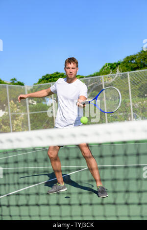 Campo da tennis. Giocatore di Tennis di colpire la sfera in volley dalla rete. Atleta maschio giocare all'aperto su hard court praticanti in estate. Giovane uomo caucasico sano vivente active fitness sport stile di vita al di fuori. Foto Stock