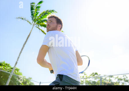 Tennista la finitura servono a giocare all'aperto. Uomo servono per gioco durante il fuori gioco di tennis. Montare atleta maschio sano vivente fitness sport stile di vita. Giovani modello caucasica nel suo 20s. Foto Stock
