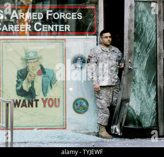 Un ufficiale militare sta dietro la porta danneggiata e un mucchio di vetro frantumato giace ai piedi di uno zio Sam poster dopo una piccola bomba danneggia il reclutamento militare stazione in Time Square il 6 marzo 2008 a New York. Poco danno era stato fatto e nessuno è stato ferito nel pre-alba attacco causato da un piccolo esplosivo concepire. (Monika Graff/UPI foto) Foto Stock