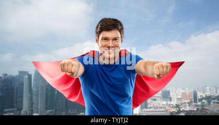 Uomo in rosso superhero cape sopra la città di Singapore Foto Stock