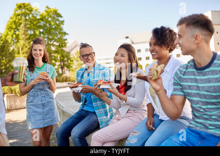 Amici mangiando panini o hamburger in posizione di parcheggio Foto Stock