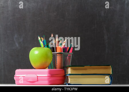 Impostare per lo studente. Una pila di libri, un apple, scatola di pranzo, matite contro lo sfondo della scuola scheda di nero. Il concetto di istruzione. Copia s Foto Stock