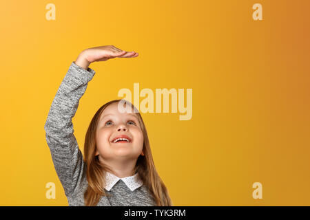 Closeup ritratto di una bambina su uno sfondo giallo. Le misure del bambino la sua altezza. Foto Stock