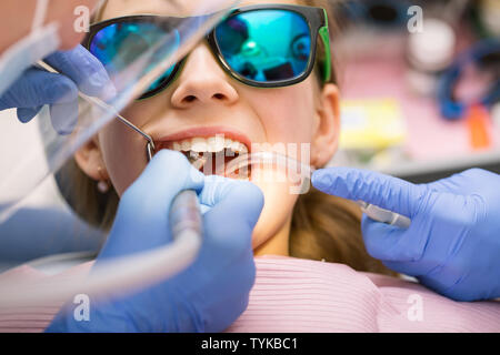 Dentista dentale di eseguire la procedura di rifornimento per preteen girl in pazienti pediatrici clinica dentale. Medico rimozione carie utilizzando ad alta velocità trapano dentale. Bambino è Foto Stock